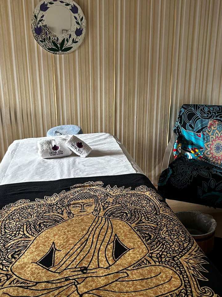 Sala de atendimento com maca e tapeçaria de Buda